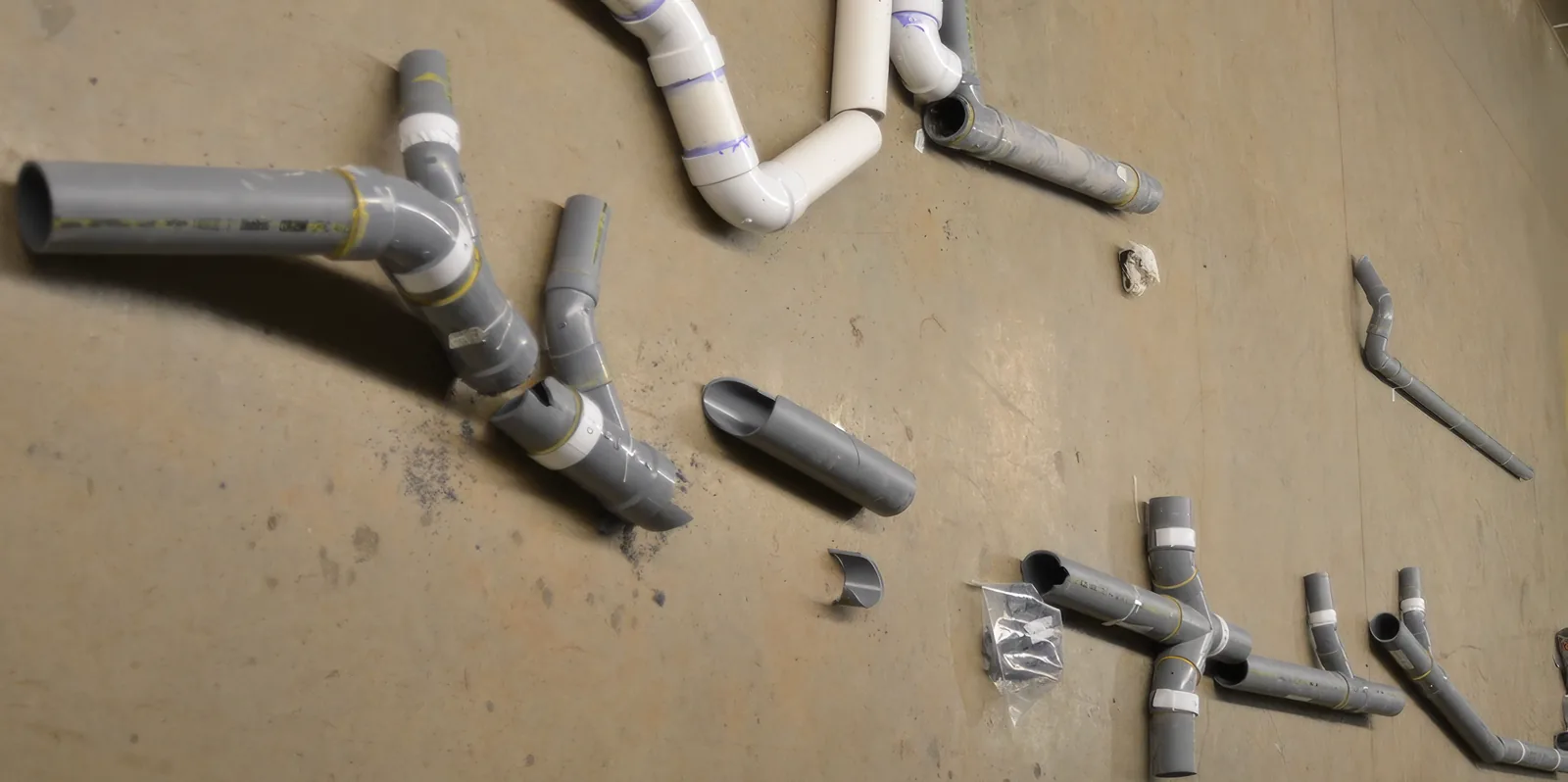 Gray CPVC drain piping and fittings removed from hospital laboratory sinks, cut into sections and laid out for examination after failing within months of installation.