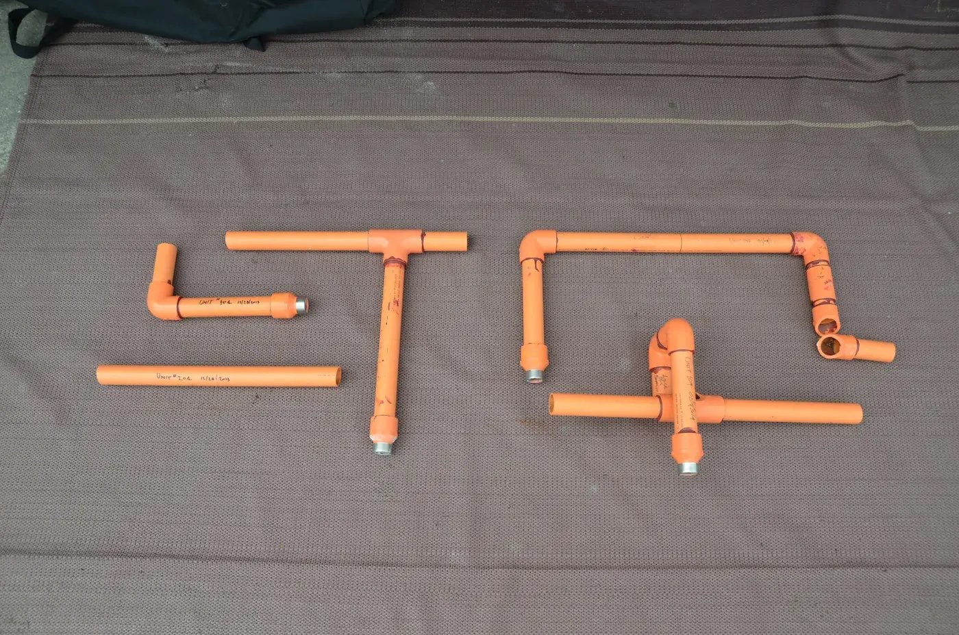 Orange CPVC fire sprinkler pipe specimens laid out for forensic failure pattern analysis