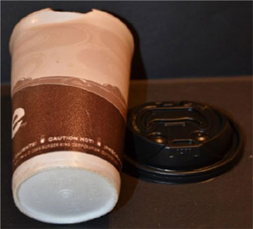 The failed takeaway coffee cup photographed beside its detached black lid