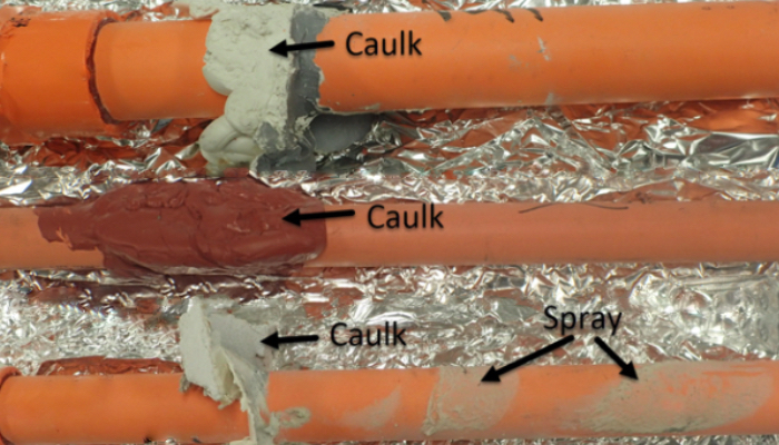 Three orange CPVC pipes running through foil-faced insulation, with arrows labelling caulk deposits at three joints and overspray on the pipe surface