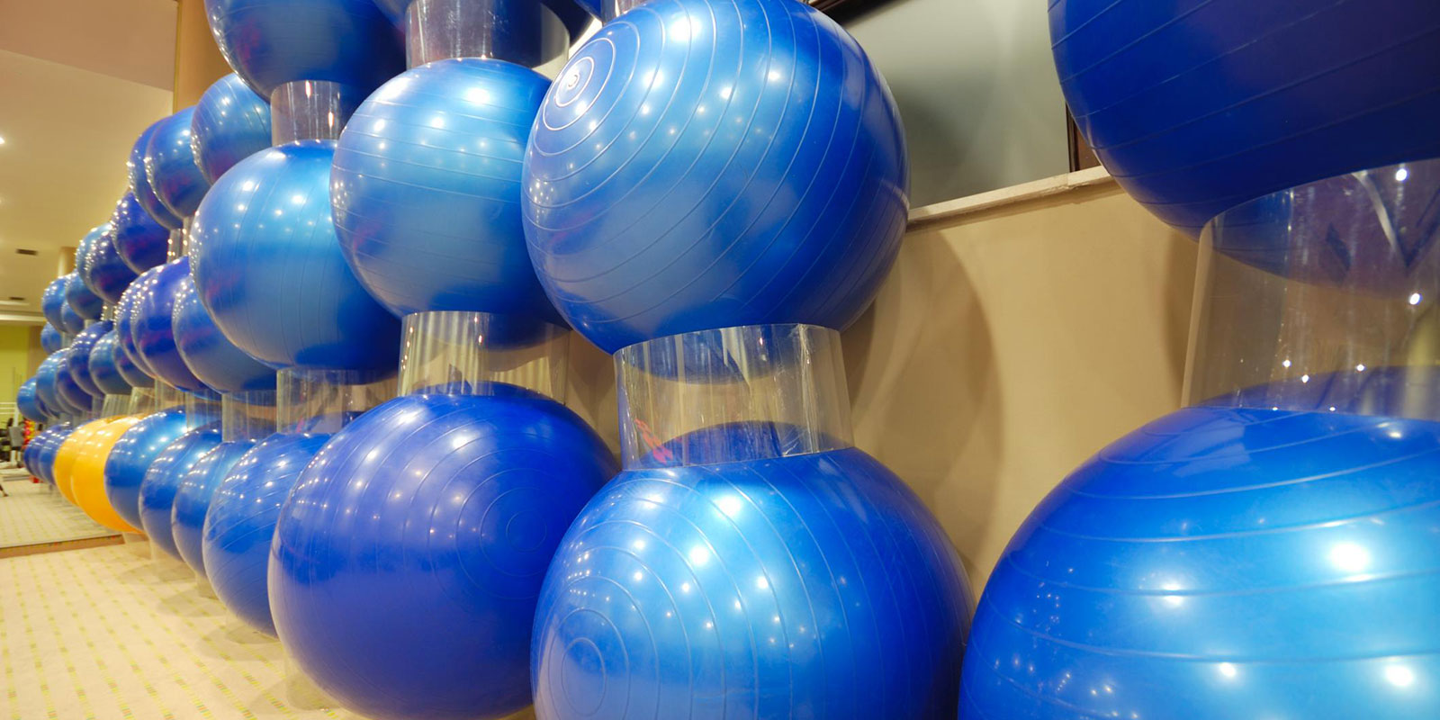 A row of inflated blue exercise balls stacked together on a rack