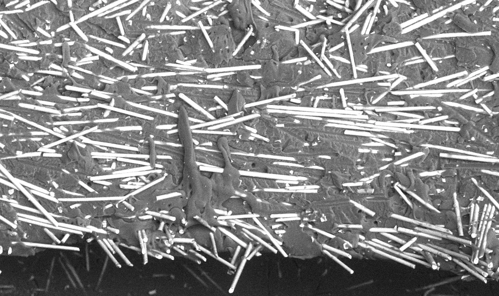 Scanning electron micrograph of a knit line fracture surface, with bright glass fibres lying parallel to the fracture rather than bridging across it