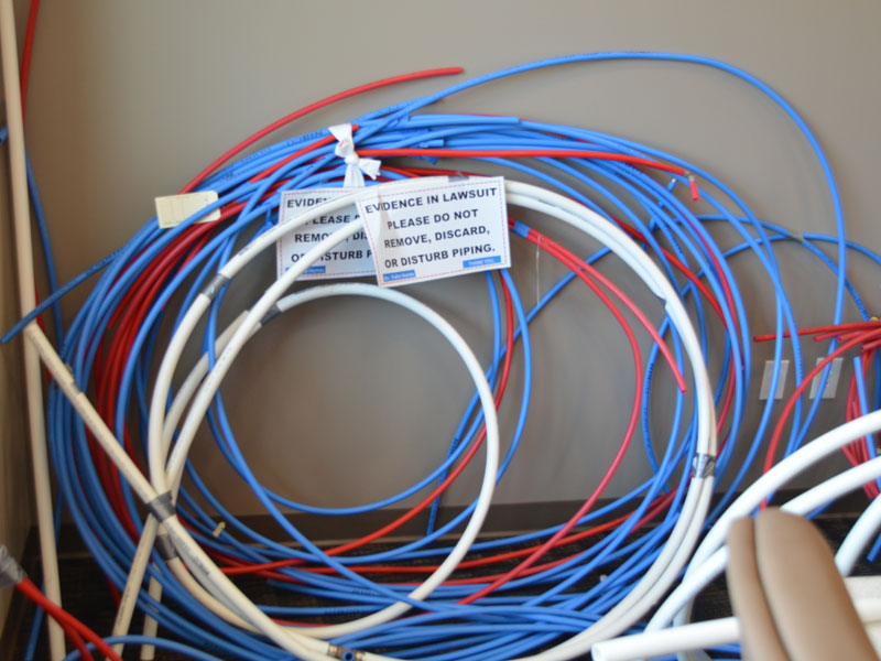 Coils of PEX tubing in blue, red and white with a paper label tag