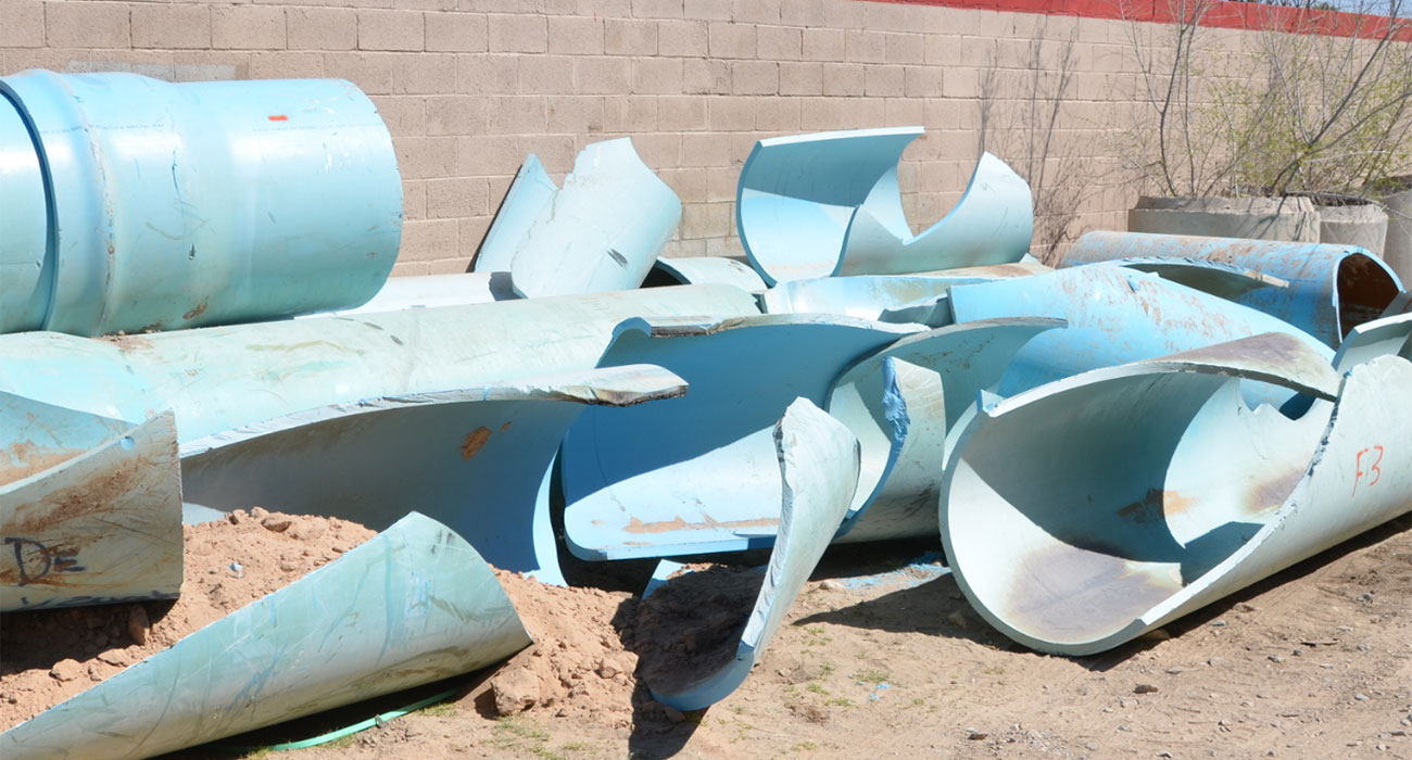 Shattered white plastic pipe fragments lying on soil, with the broken sections exposing the pipe interior