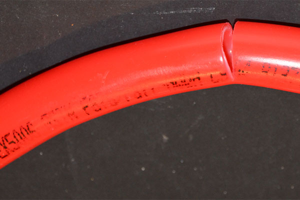 Close-up of a curved red PEX tube against a dark background