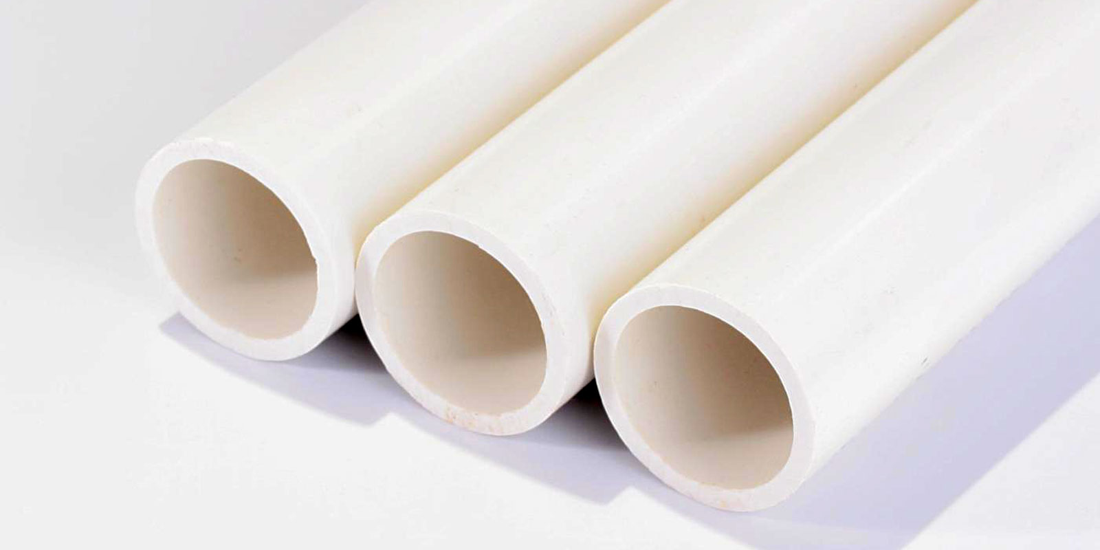 Three clean cream-coloured plastic pipe sections arranged on a light background