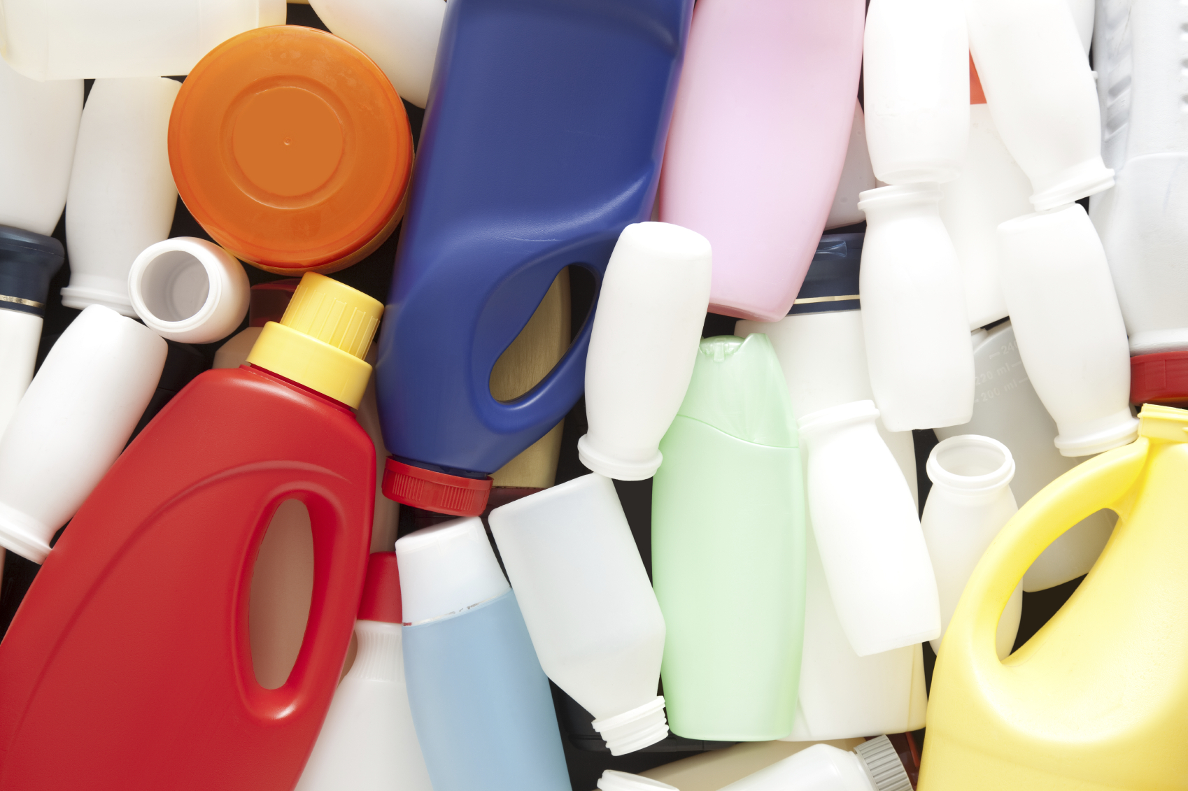 A dense arrangement of assorted moulded plastic bottles, jars and caps in many colours