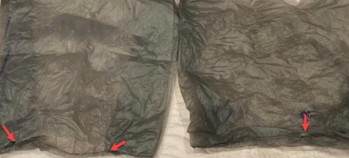 Two failed retail plastic bags with arrows marking the failure points